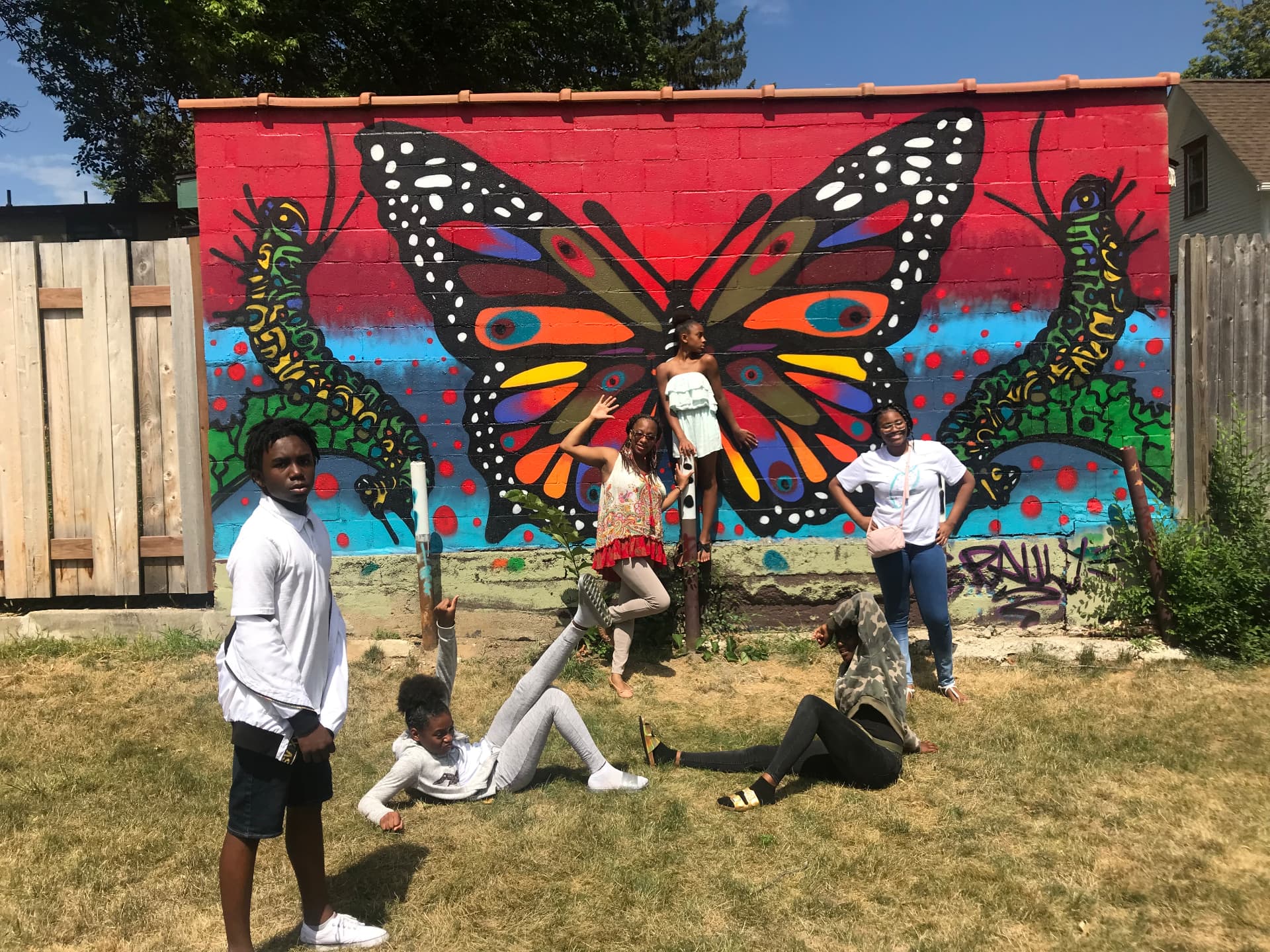 FliKidz youth gathered in front of a colorful butterfly mural